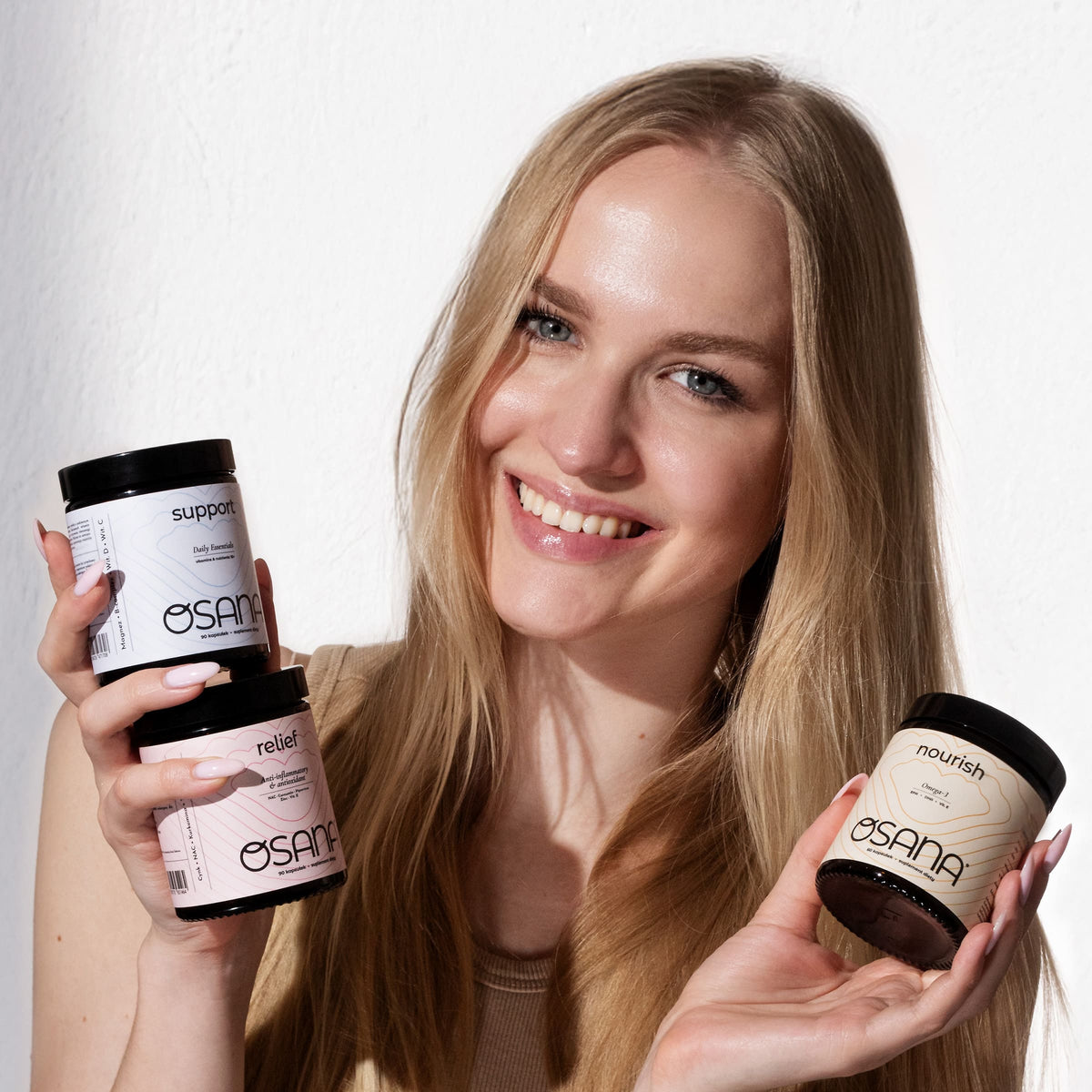 Uśmiechnięta kobieta trzyma trzy słoiki zestawu Osana Holistic Balance Trio